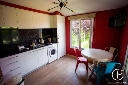 a kitchen with a table and a sink and a washing machine at Casas do Picoutinho in Ponte de Lima