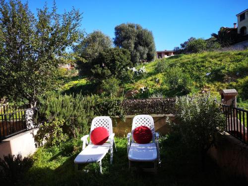 two chairs with red pillows sitting in the grass at Sunny garden house in Villasimius