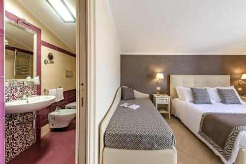 a bedroom with a bed and a bathroom with a sink at Vittorio Emanuele Boutique Hotel in Sciacca