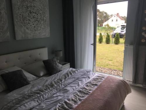 a bedroom with a bed and a large window at Studio 33 z Ogrodem in Pogorzelica