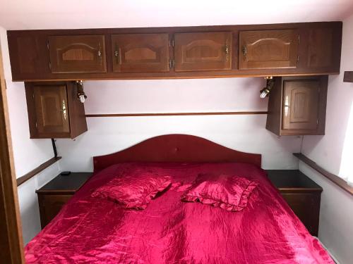 Una cama roja en una habitación con armarios de madera. en Großer Familien-Wohnwagen, en Dobbertin