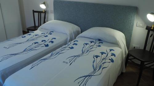 two beds in a room with blue and white sheets at R&B Giardino 34 in Forlì