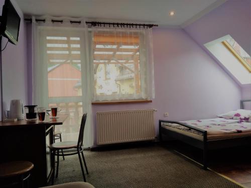 sypialnia z łóżkiem, stołem i oknem w obiekcie Na Skwerku w Stroniu Śląskim
