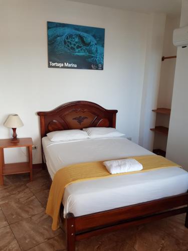 a bedroom with a bed with white sheets at Gloria - Galápagos Inn in Puerto Ayora