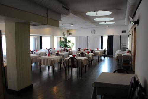 een eetkamer met witte tafels en stoelen en een klok bij Hotel Selide in Desio