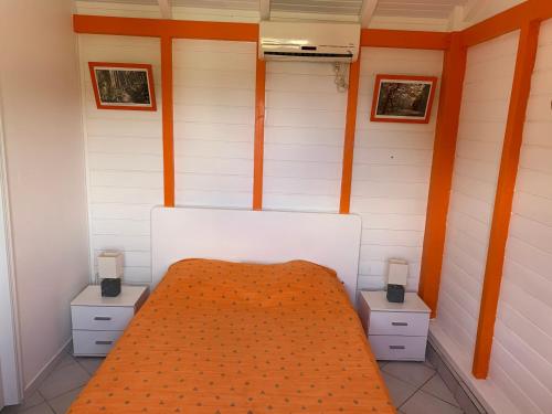 a small room with a bed and two night stands at Bungalow les Cerisiers in Bouillante