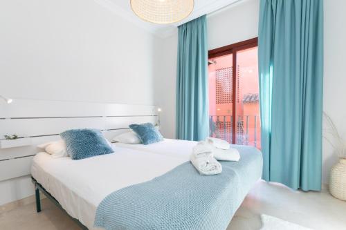 1 Schlafzimmer mit 2 Betten, blauen Vorhängen und einem Fenster in der Unterkunft JDC Beach Side Marbella in Marbella