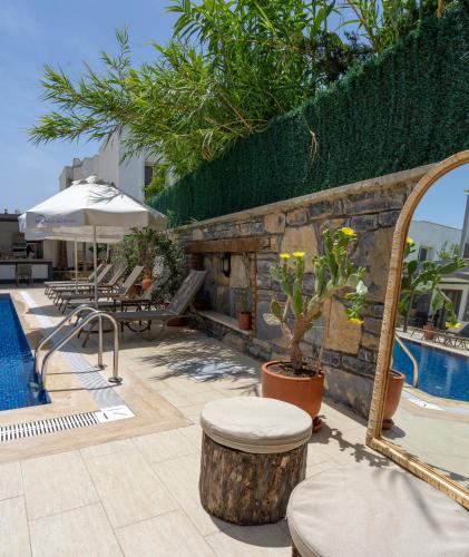 a pool with a stone wall next to a resort at Maye Residence in Gümbet