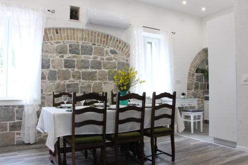 a dining room with a table and a stone wall at Old school apartment in Kaštela