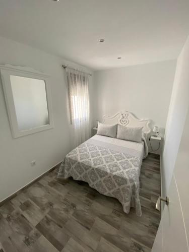 a white bedroom with a bed and a mirror at Conil Apartment in Conil de la Frontera