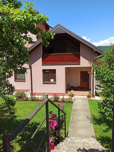 een roze huis met een hek en bloemen bij Apartman Vukan in Bajina Bašta