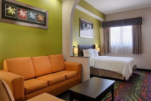 a hotel room with a bed and a couch at Days Inn & Suites by Wyndham Bonita Springs North Naples in Bonita Springs