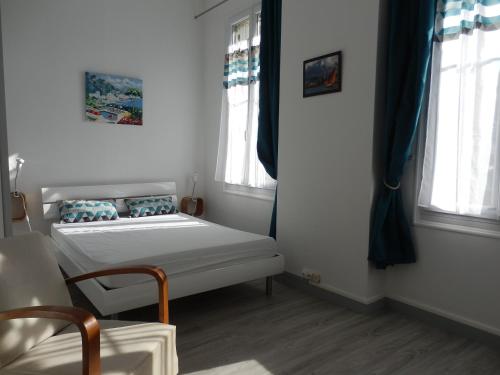 Cette petite chambre comprend un lit et deux fenêtres. dans l'établissement Appartement T2 ou T1 côté cour/jardin avec garage, à Rochefort