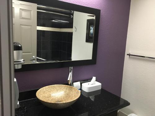 a bathroom with a granite sink and a mirror at Days Inn & Suites by Wyndham Bonita Springs North Naples in Bonita Springs