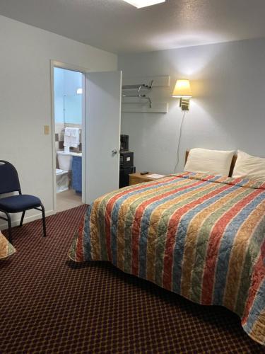 a hotel room with a bed and a chair at Regency Inn Comanche in Comanche