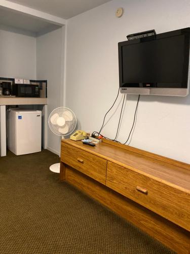 a flat screen tv on top of a wooden dresser at Regency Inn Comanche in Comanche