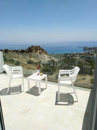 two white chairs and a table on a balcony with the ocean at Bouganville Bed & Breakfast Stegna in Archangelos