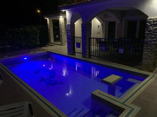 a swimming pool with blue lighting in a house at night at Villa KRK-4 bedrooms, 4 bathrooms with heated pool and jacuzzi, 150m from the sea in Krk