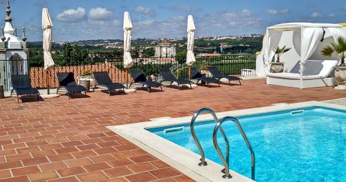 a swimming pool with chairs and a gazebo at Hotel Real d Obidos in Óbidos