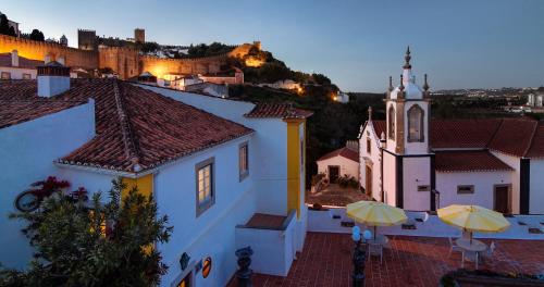 a view of a town with umbrellas and a church at Hotel Real d Obidos in Óbidos