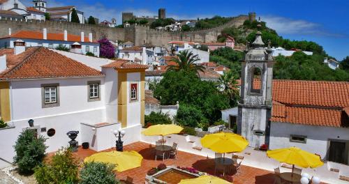 a group of tables with yellow umbrellas in front of a building at Hotel Real d Obidos in Óbidos