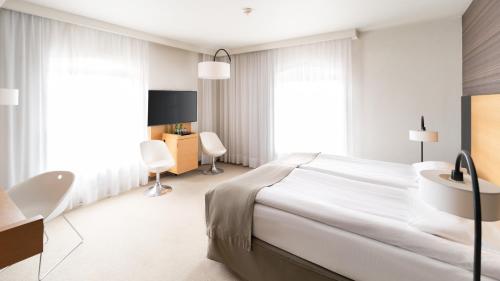 a white bedroom with a large bed and a desk at Hotel Bulwar in Toruń