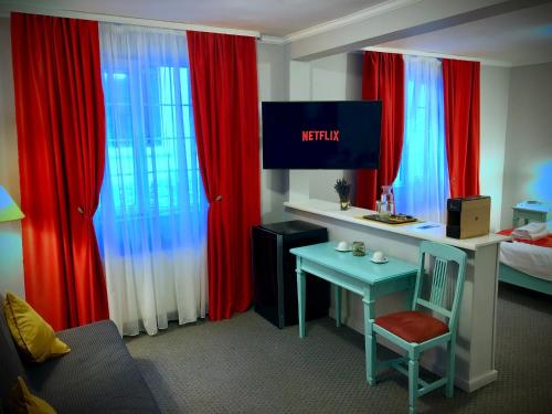 a bedroom with red curtains and a desk and a bed at Vila De Argint in Sinaia