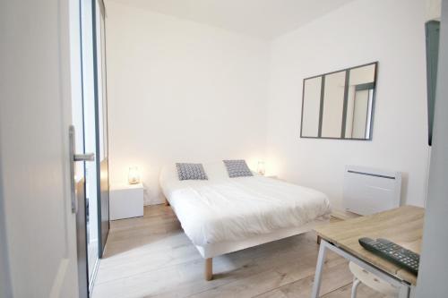 a white bedroom with a bed and a mirror at Villers-sur-Mer in Villers-sur-Mer