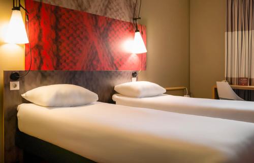 two beds with white pillows in a hotel room at Ibis Irun in Irún