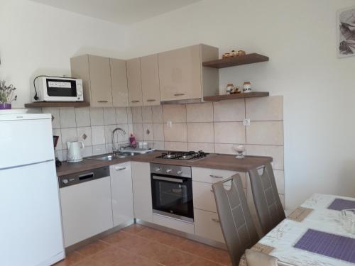 a small kitchen with white appliances and a microwave at Apartmani Roza Lopar in Lopar