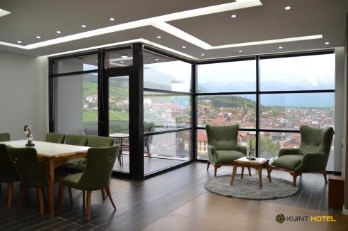 a dining room with a table and chairs and windows at Kuint Hotel in Peje