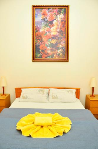 a yellow blanket on a bed with a painting on the wall at Central Area Apartments in Kyiv