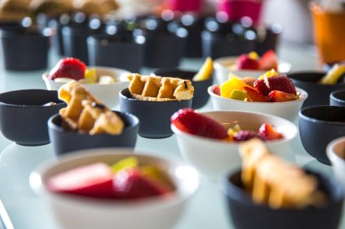 a table topped with bowls of fruit and waffles at Park Inn by Radisson Jeddah Madinah Road in Jeddah