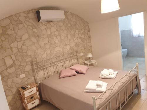 una camera con letto e parete in pietra di AP Apartment - Spiaggia della Purità a Gallipoli