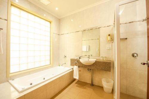 a bathroom with a tub and a sink and a bath tub at Strath Motel in Strathalbyn