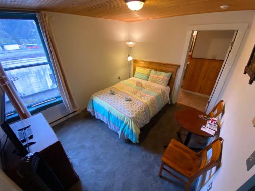 a small bedroom with a bed and a table at Historic Hotel Bayview in Stewart