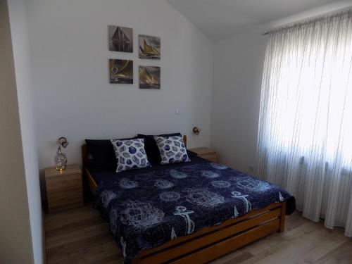 ein Schlafzimmer mit einem Bett mit blauer Decke und einem Fenster in der Unterkunft Villa Jukic in Murter