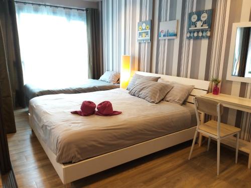 Un dormitorio con una cama con dos zapatos rojos. en Rain by Lazy Sea Beach House en Cha Am