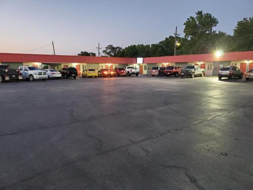 a parking lot with cars parked in front of a store at Guest House Motel in Carthage