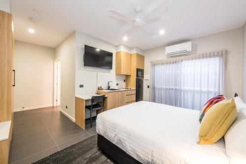 a bedroom with a bed and a desk and a kitchen at AVENUE MOTEL APARTMENTS in Toowoomba