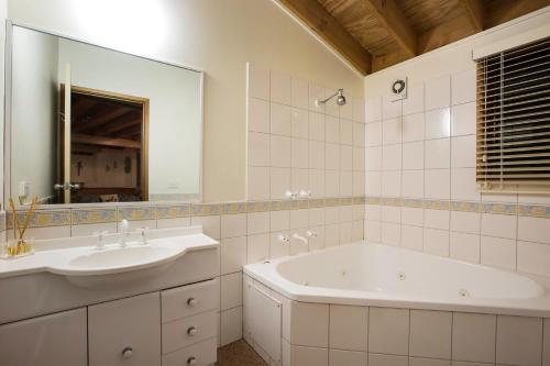Un baño con bañera, lavabo y espejo. en Kummonin, en Dinner Plain