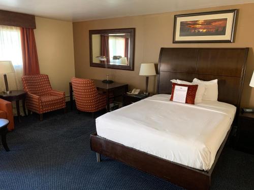 a hotel room with a bed and a chair at Travelodge by Wyndham Rapid City in Rapid City