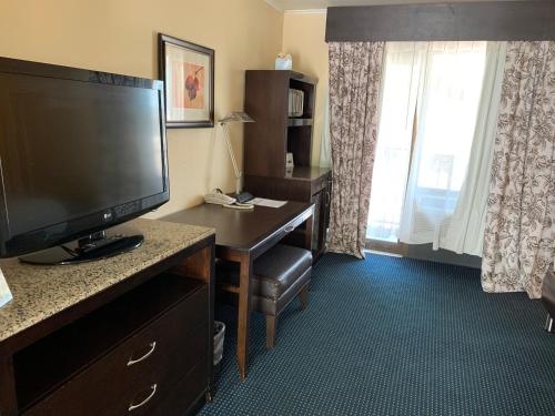 a hotel room with a desk with a large screen television at Travelodge by Wyndham Rapid City in Rapid City