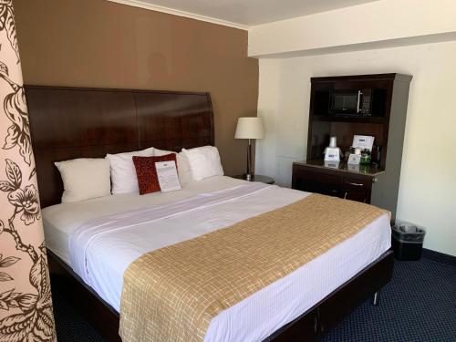 a hotel room with a large bed with white sheets at Travelodge by Wyndham Rapid City in Rapid City