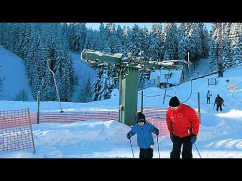 a man and a child on skis on a ski lift at Penzion "Apartmány U Semušky" in Pernink