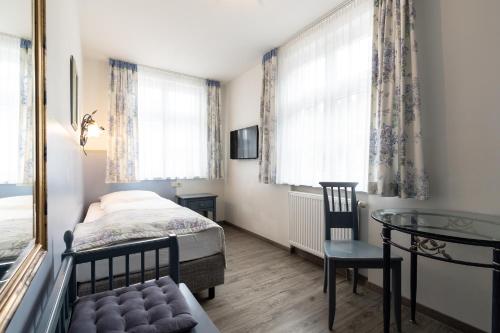 a bedroom with a bed and a table and window at Hotel Gasthof Rössle in Weingarten