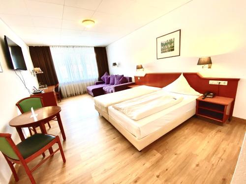 Hotel Garni Rebgarten في رافنسبرغ: غرفة فندقية بسرير وطاولة وكراسي