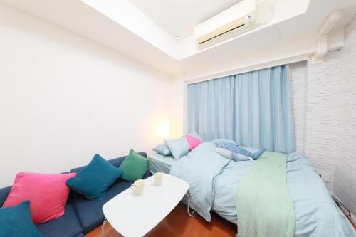 a living room with a blue couch with colorful pillows at IBASHO ShibuyaDogenzaka803 in Tokyo