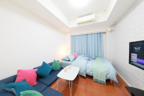 a living room with a blue couch with colorful pillows at IBASHO ShibuyaDogenzaka803 in Tokyo