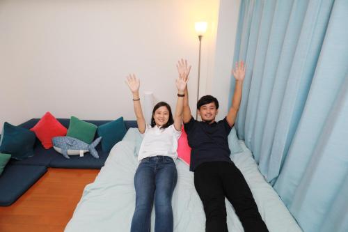 a man and a woman sitting on a bed at IBASHO ShibuyaDogenzaka803 in Tokyo